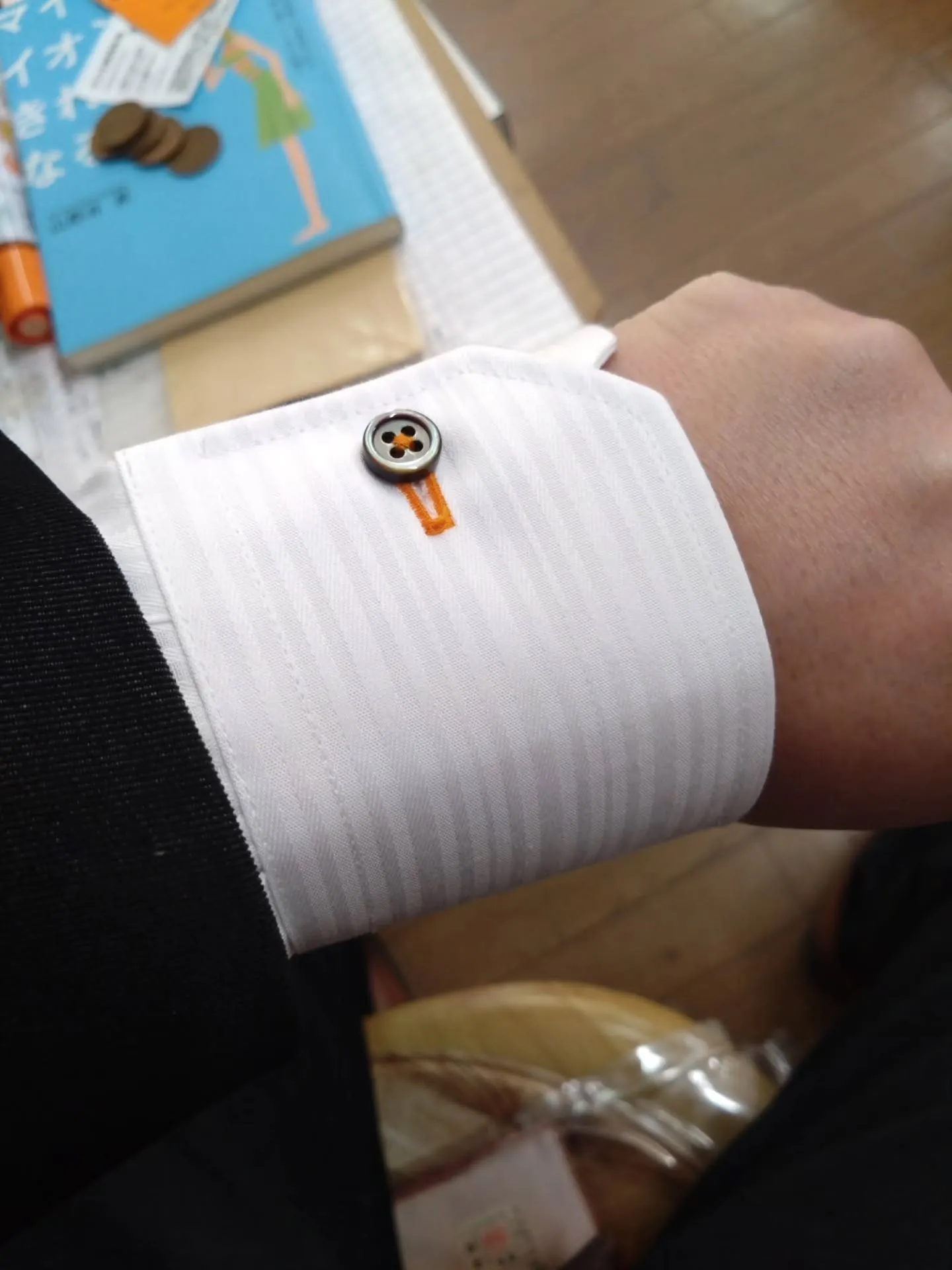 今回のオーダーシャツのこだわりは、オレンジの糸と黒い貝ボタン...